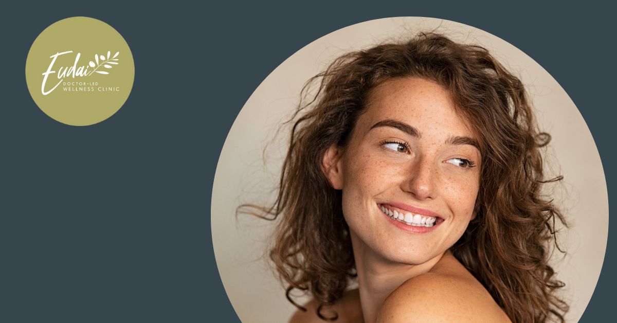 Eudai Clinic logo alongside a portrait of a young woman with curly hair and freckles, smiling confidently against a neutral background.