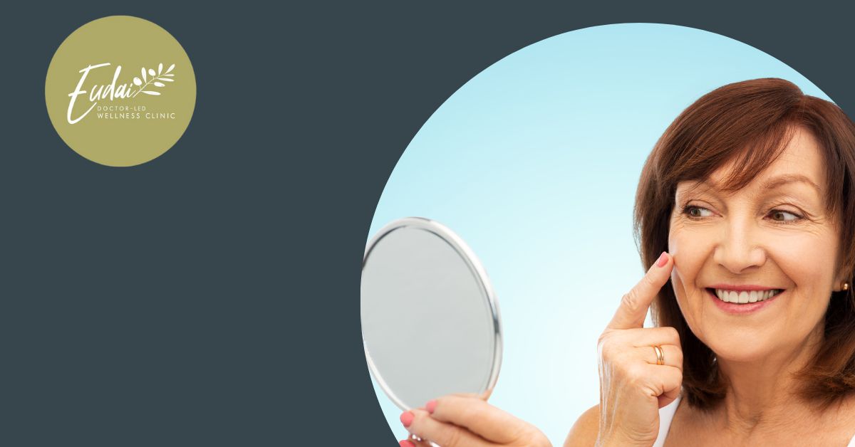 Eudai Clinic logo alongside a portrait of a middle-aged woman smiling and pointing to her face while holding a hand mirror against a light blue background.